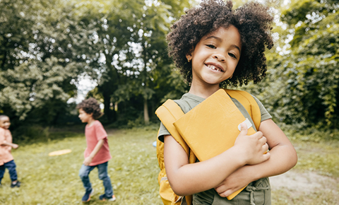 Kid with book wearing backpack