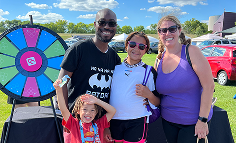 Family smiling at CCCU table at Market Fest